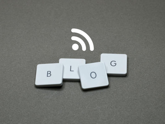 Four letter tyles spelling out the word blog, with an RSS feed icon above it, against a grey background