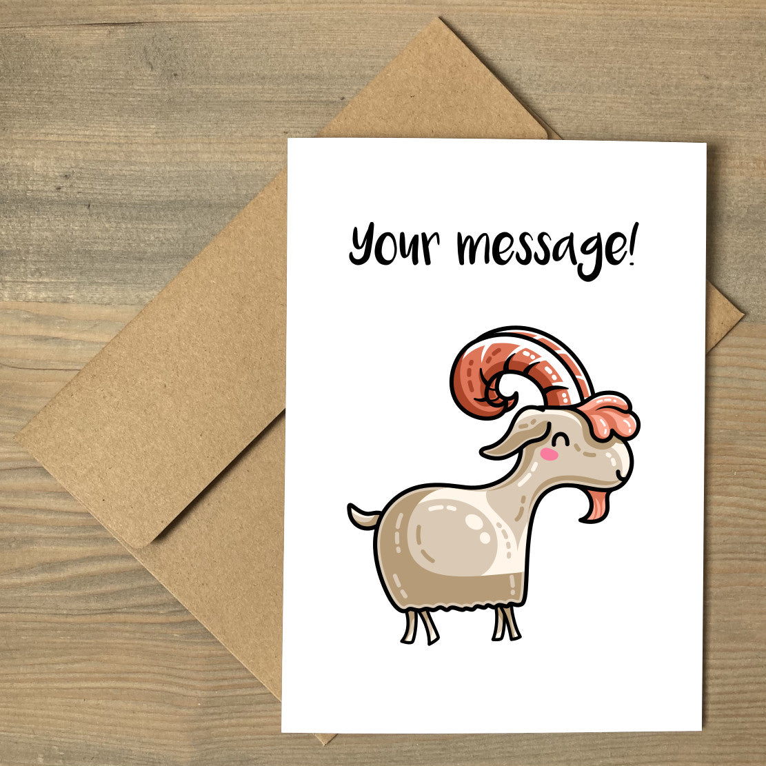 A white greeting card lying flat on a brown envelope, with a design of a kawaii cute goat with rust coloured antlers and beard and a personalised message above