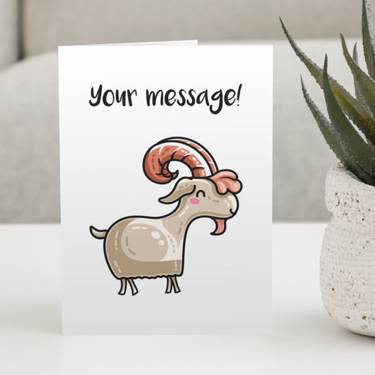 A white greeting card standing on a white table, with a design of a kawaii cute goat with rust coloured antlers and beard and a personalised message above