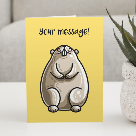 A yellow greeting card standing on a white table with a design of a kawaii cute groundhog sitting up facing the front, with a personalised message above