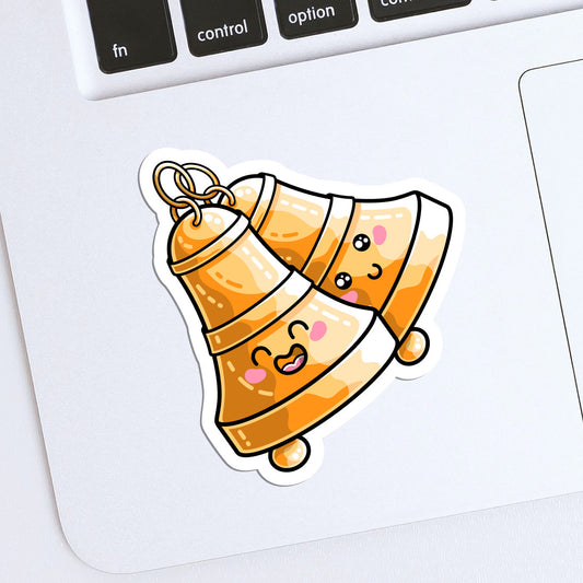 The corner of a laptop keyboard with a die cut vinyl sticker of two cute bells with happy faces attached at the top by rings stuck onto it