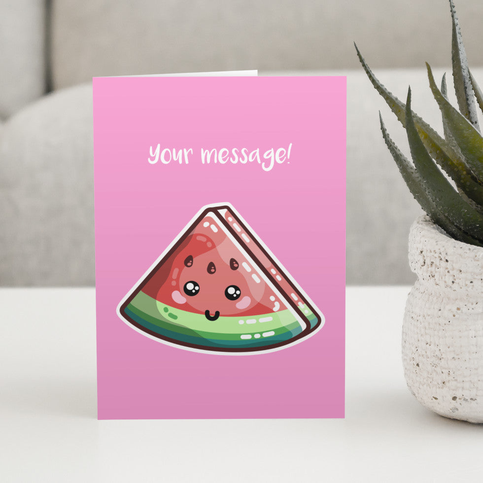 A pink greeting card standing on a white table, with a design of a kawaii cute slice of watermelon and personalised with a message above