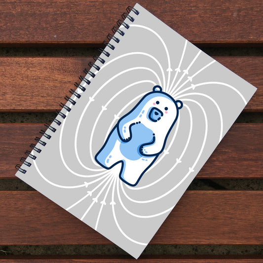 A grey spiral bound notebook with a kawaii cute white polar bear with blue shading surrounded by white magnetic field lines.