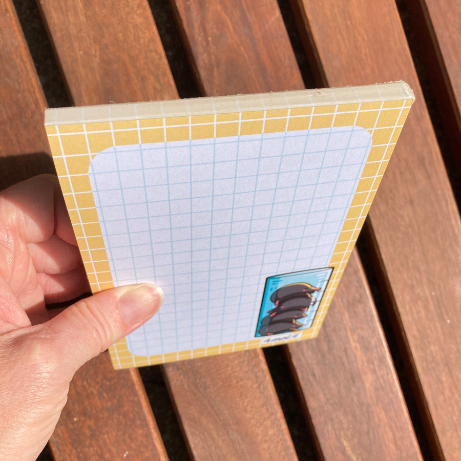The notepad being held at an angle to see the top glued edge.