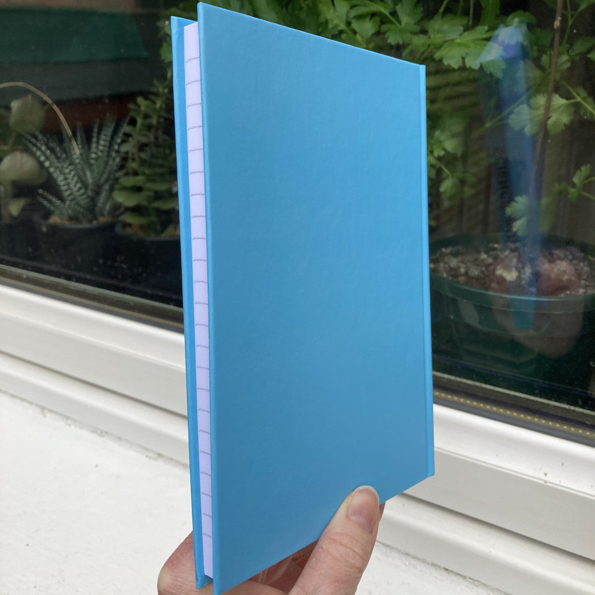 Blue hardback journal held closed showing the back
