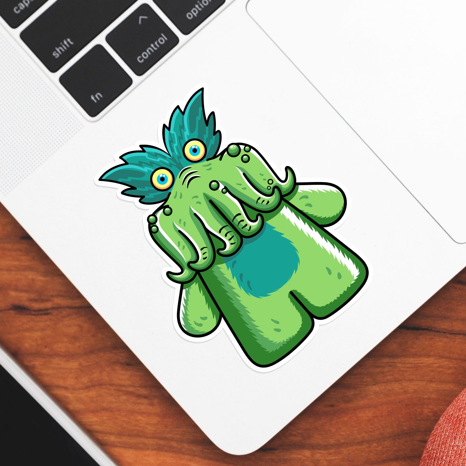 A shaped green vinyl sticker of the tickle-me-wiggly toy shown stuck onto the bottom left hand corner of a laptop computer keyboard