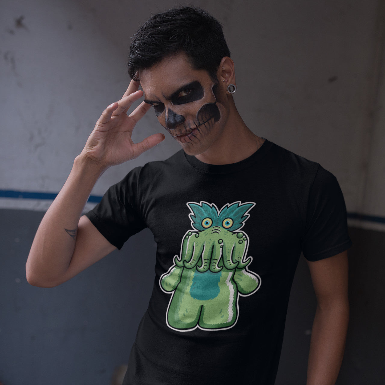 Man in Halloween makeup wearing a black cotton crewneck t-shirt of StarKid tickle-me-wiggly plush toy