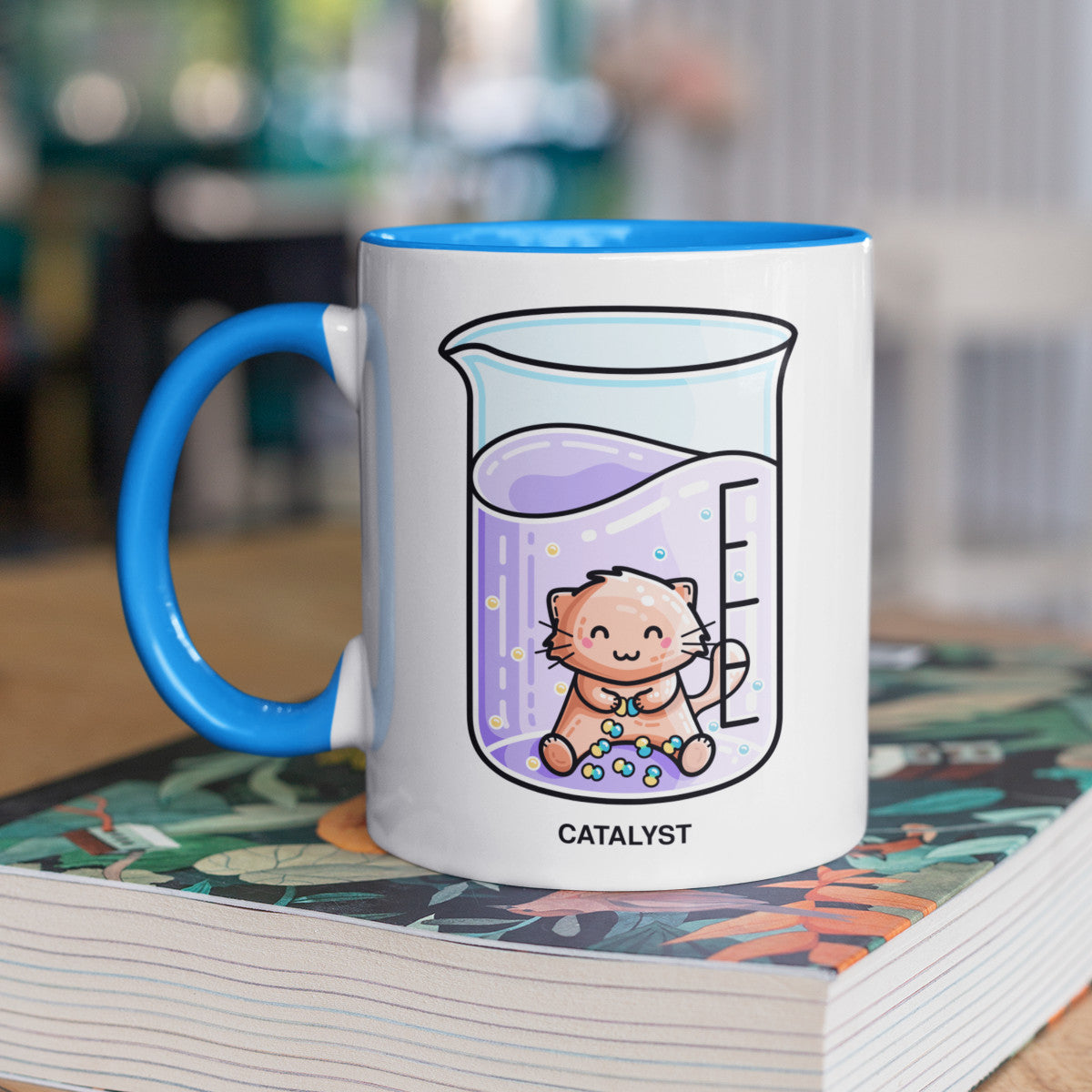Cute cat joining atoms in a chemistry beaker of liquid design on a two toned blue and white ceramic mug, showing LHS