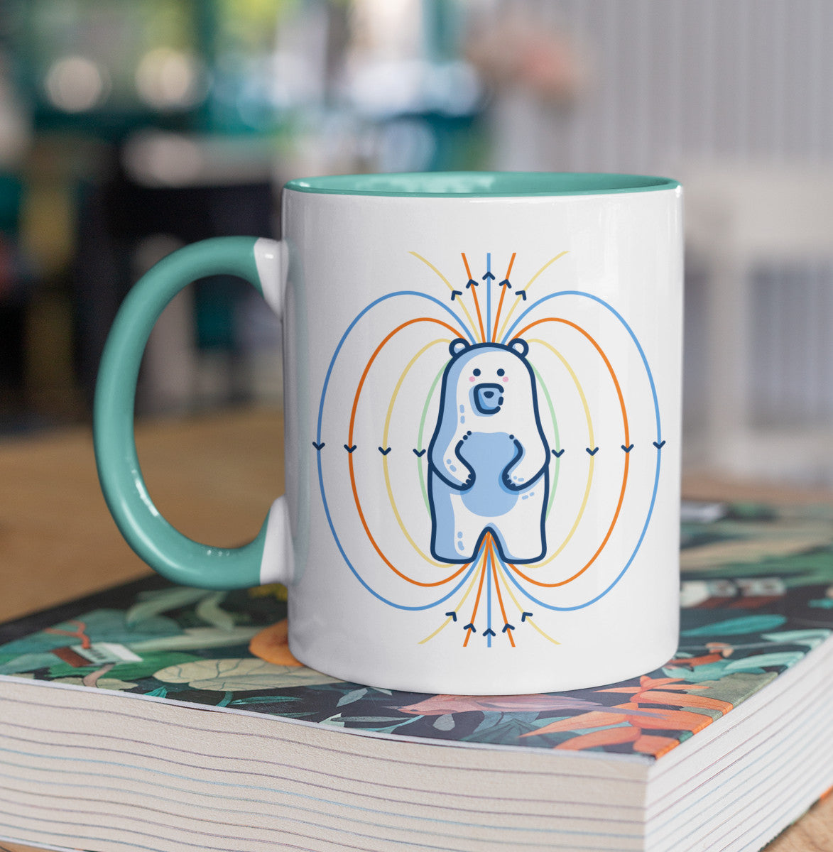 A two toned white and spearmint ceramic mug, handle to the left, with a design of a white polar bear standing up and blue, orange and yellow magnetic field lines coming out of it.