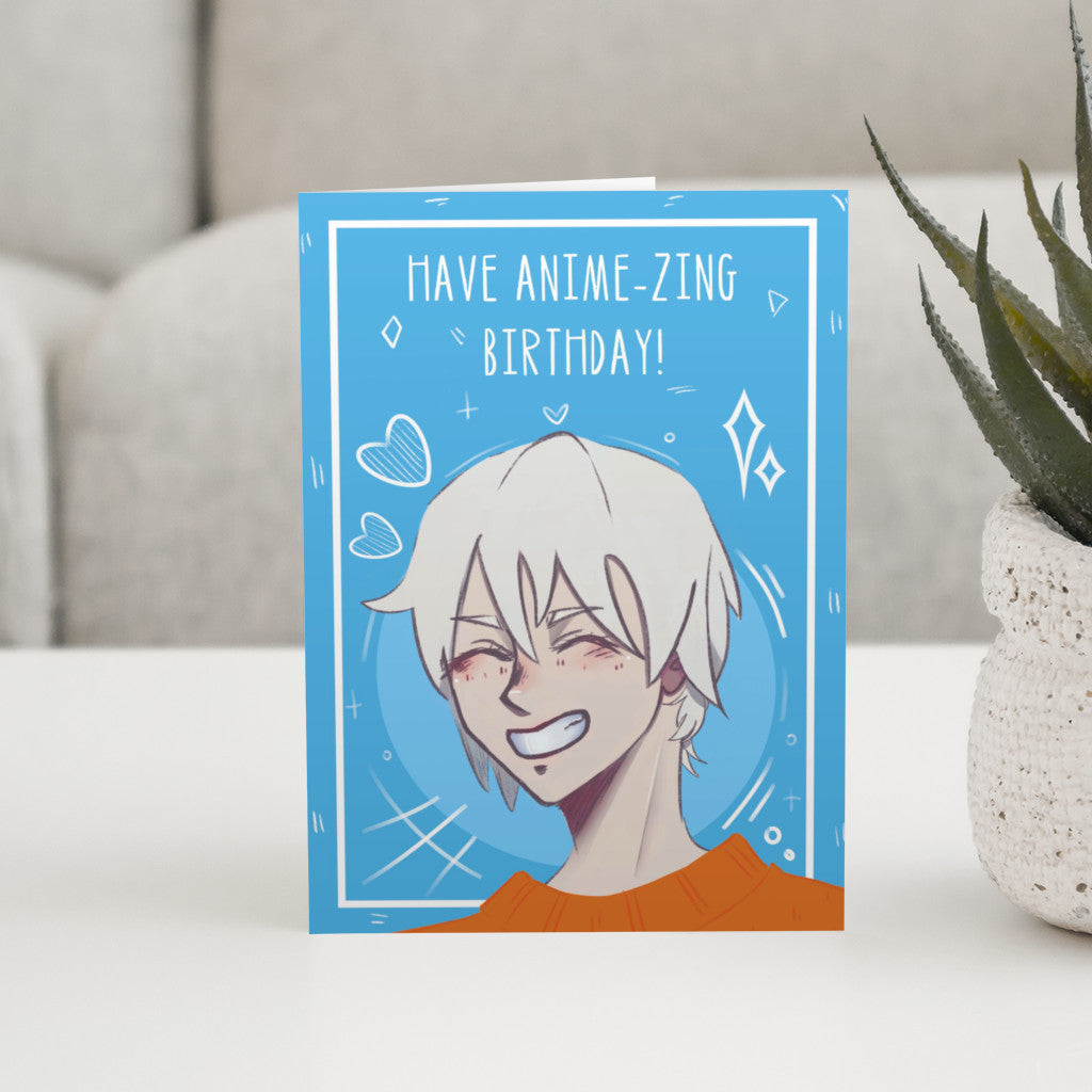 A blue card, standing, with the head and shoulders of an anime character with a huge smile, blonde hair and an orange jumper. Wording is 'have anime-zing birthday!'