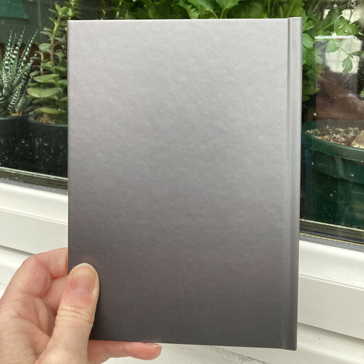 Hardback journal held in a hand showing the dark grey back
