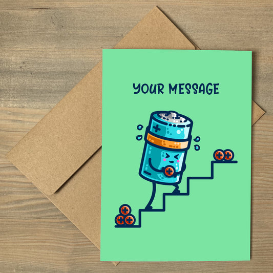 A brown envelope beneath a green greeting card with a design of a kawaii cute cylindrical blue battery working hard, sweating, carrying a positive charge up some steps and the words your message written above