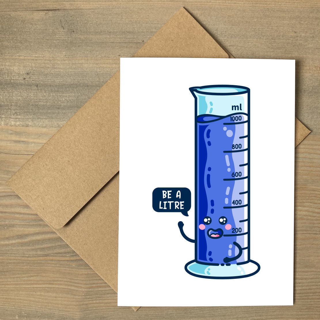 A white greeting card lying flat on a brown envelope, with a design of a happy kawaii cute blue one litre graduated cylinder with a speech bubble saying be a litre