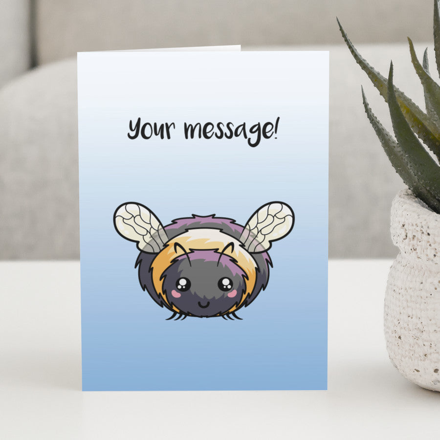 A blue and white gradient greeting card standing on a white table with a design of a kawaii cute bee with a personalised message above.