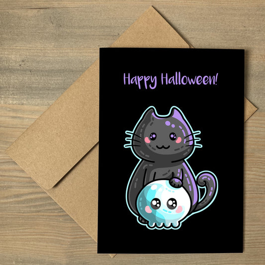 A brown envelope beneath a black greeting card that features a kawaii cute black cat with its paw on a blue skull with a personalised message above.