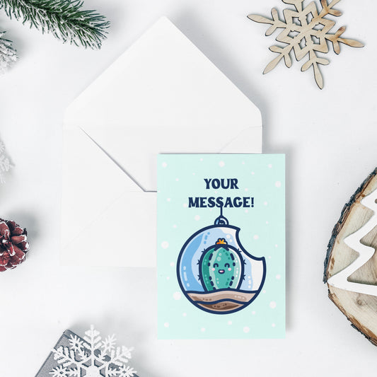 An open white envelope beneath a pale turquoise greeting card with a design of a kawaii cute happy green cactus succulent planted in a transparent hanging bauble terrarium with the words your message above.
