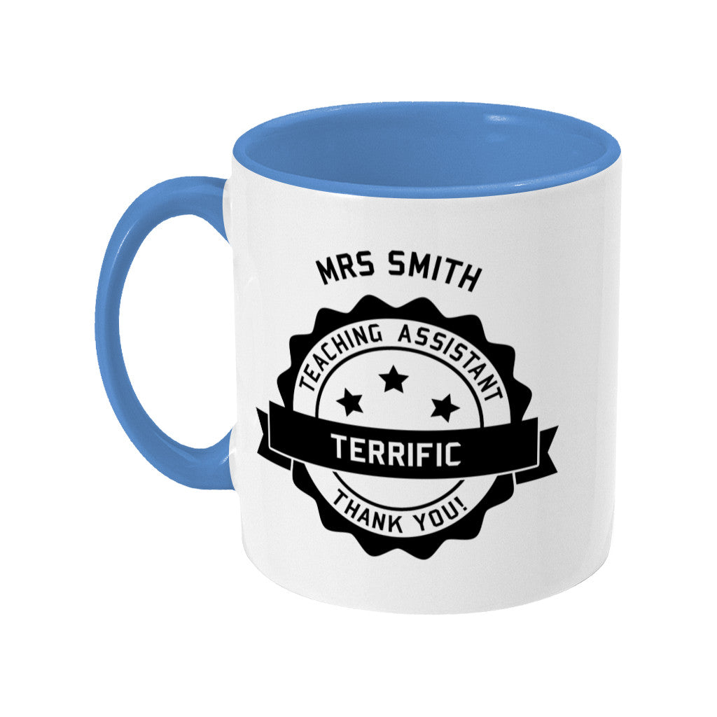 Personalised black circular banner design with the words 'terrific teaching assistant' on a two toned blue and white ceramic mug, showing LHS