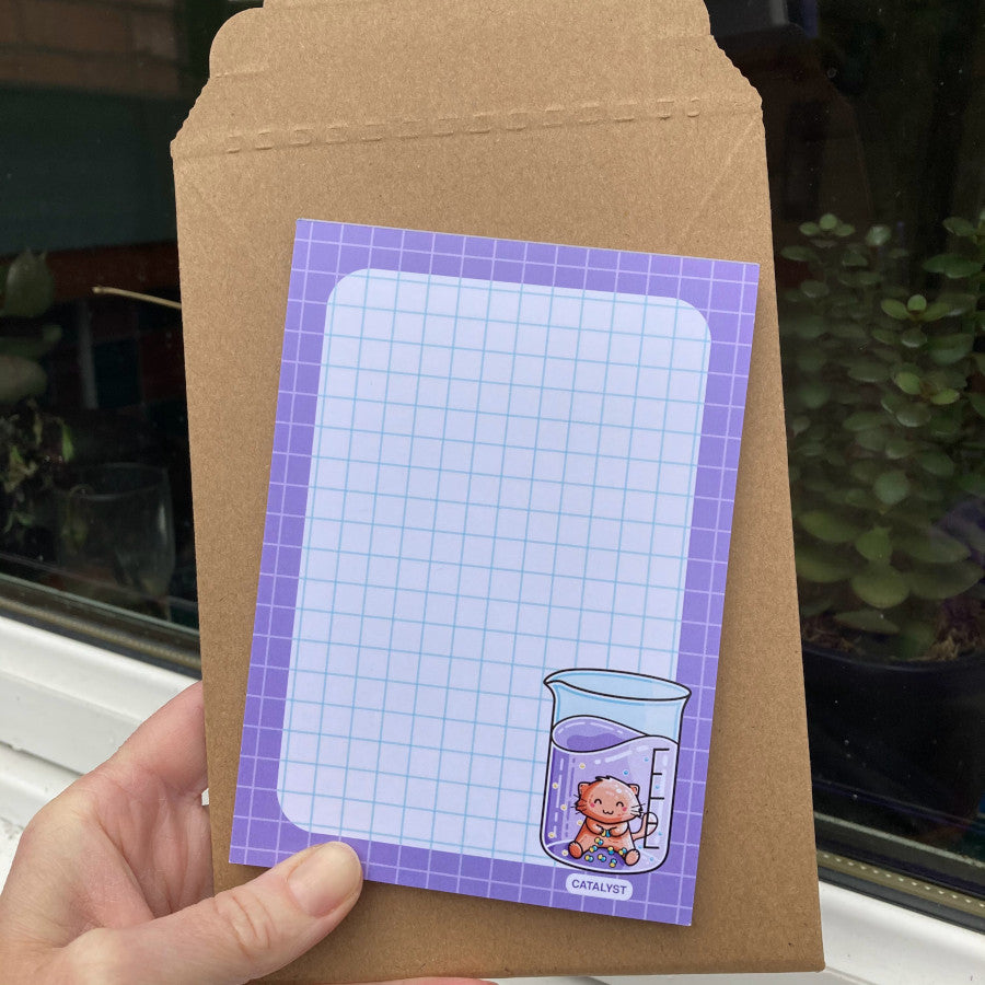 A notepad held in front of a rigid brown cardboard packaging envelope.