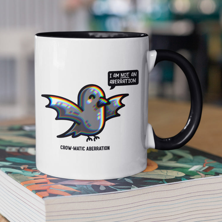 A two toned white and black ceramic mug, handle to the right, featuring a kawaii cute crow with chromatic aberration. A speech bubble says I am NOT an aberration.