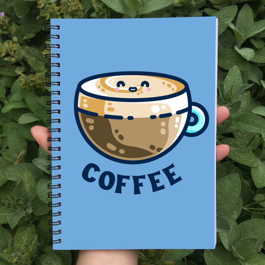 Closed spiral notebook with a blue cover featuring a design of a kawaii cute glass cup of creamy latte with the word coffee beneath in dark blue capital letters