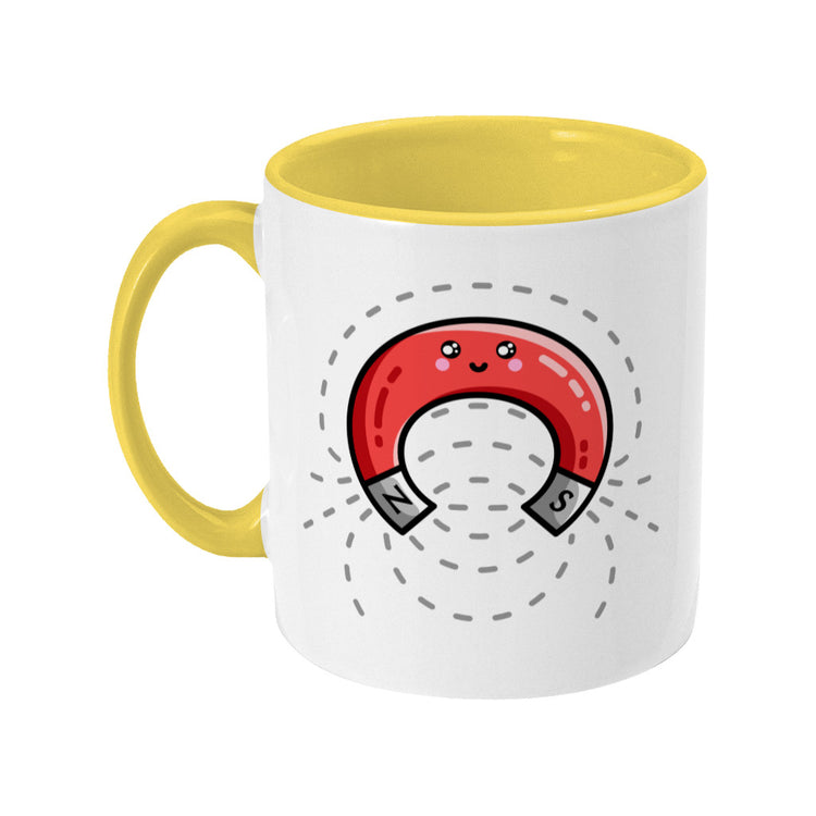 A white and yellow two toned ceramic mug, with the handle to the left, and a design of a cute red magnet with magnetic field lines.