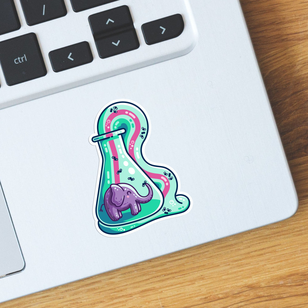 The bottom right hand corner of a laptop computer keyboard with a die cut vinyl sticker on it that is the shape of the purple, pink and green elephant toothpaste design