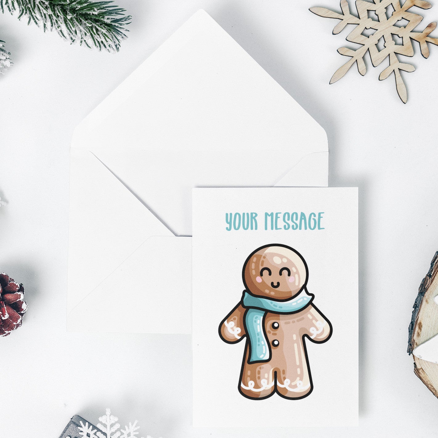 An open white envelope beneath a white greeting card with a design of a kawaii cute gingerbread person wearing a blue scarf