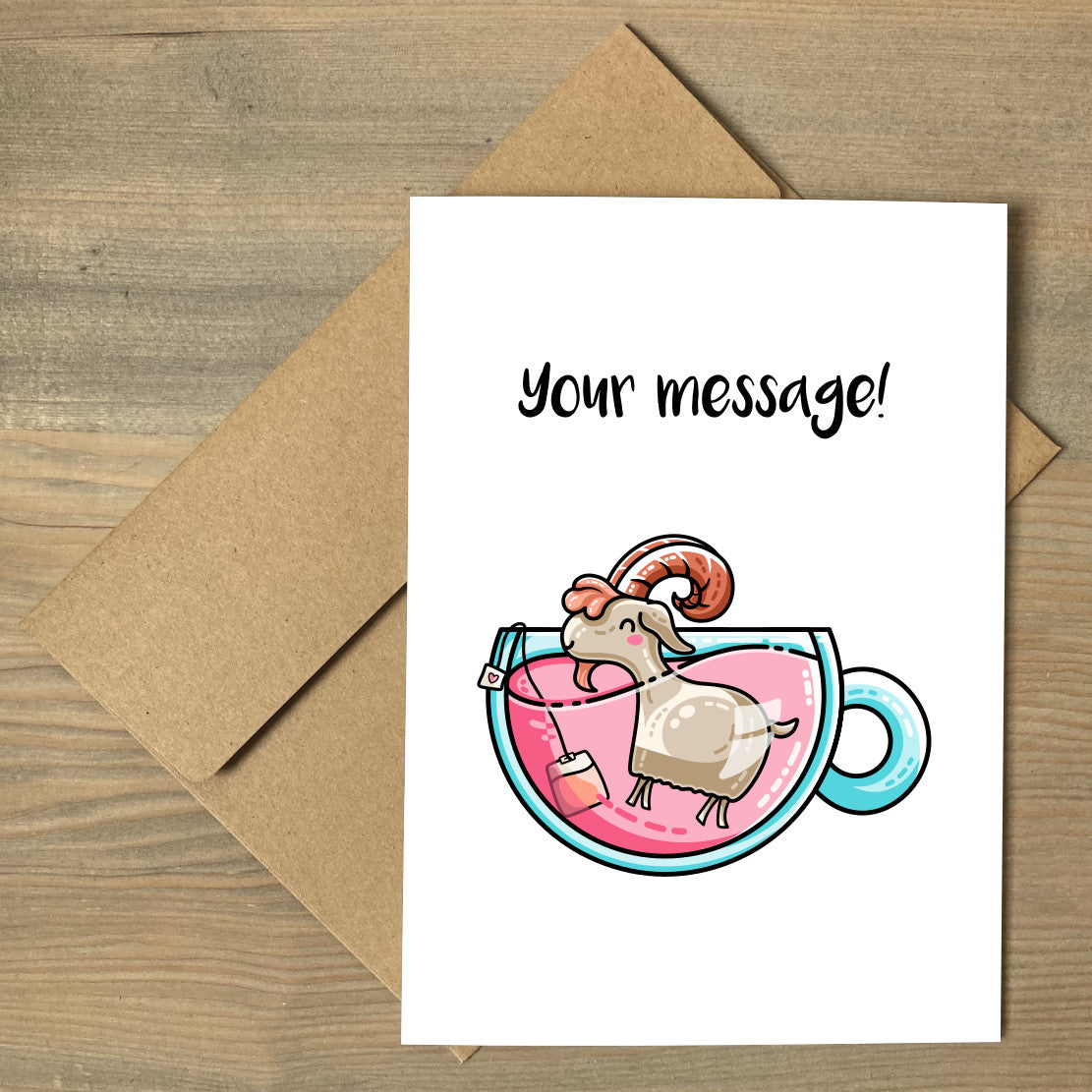 A white greeting card lying flat on a brown envelope, with a design of a cute goat in a teacup of pink liquid with personalised wording above