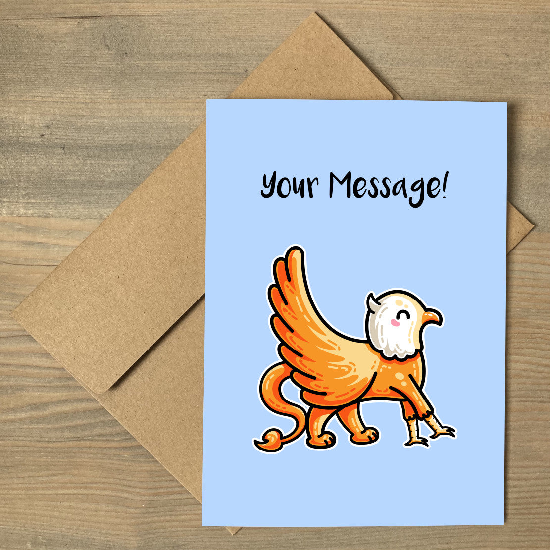 A blue greeting card lying flat on a brown envelope, with a design of a cute orange griffin walking to the right across the card, with personalised wording above