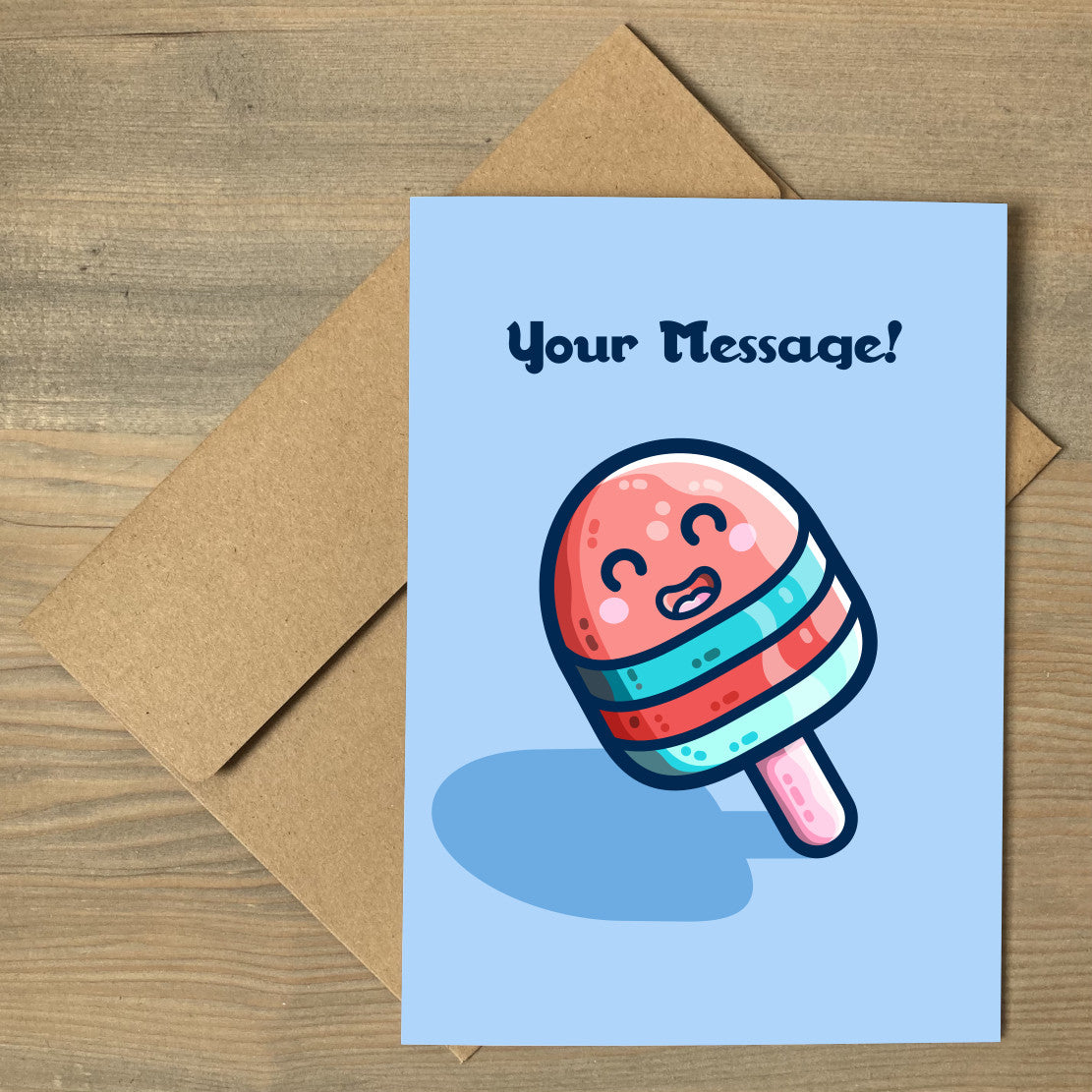 A blue greeting card lying flat on a brown envelope, with a design of a blue and red striped kawaii cute ice lolly on a stick and with a personalised message above