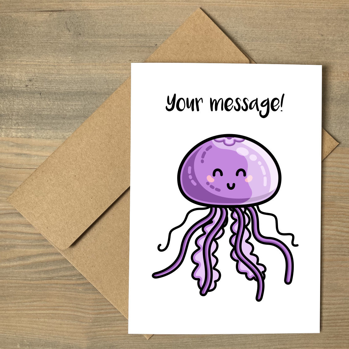 A white greeting card lying flat on a brown envelope, with a design of a kawaii cute purple jellyfish with a personalised message above