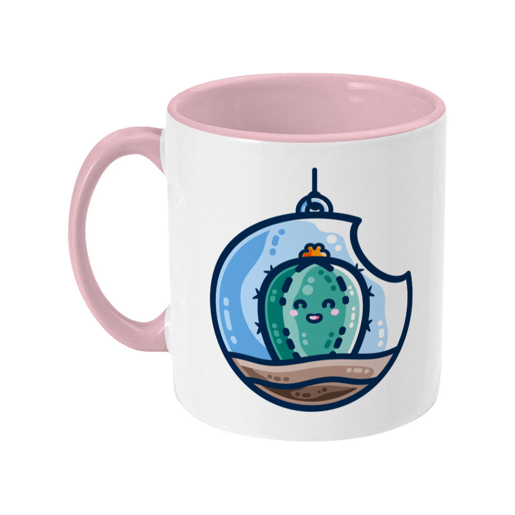 A two toned white and pale pink ceramic mug with the handle to the left showing a kawaii cute happy green cactus succulent planted in a transparent hanging bauble terrarium.
