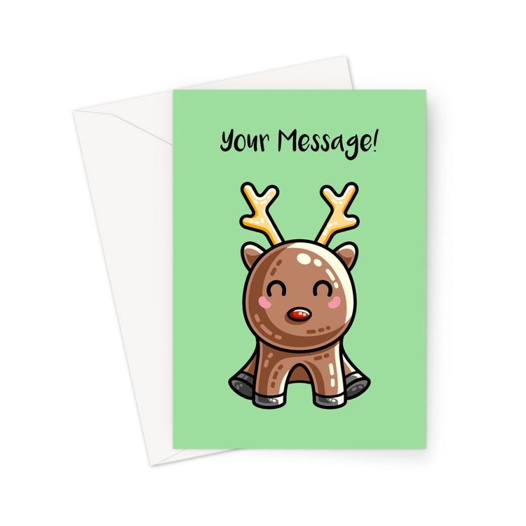 A white envelope beneath a green greeting card with a design of a kawaii cute reindeer with a red nose in a sitting position facing forward and the words Your Message in black above
