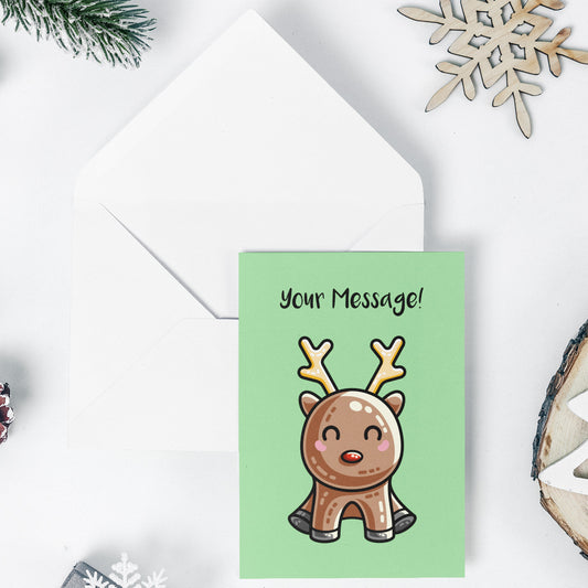 An open white envelope beneath a green greeting card with a design of a kawaii cute reindeer with a red nose in a sitting position facing forward and the words Your Message in black above