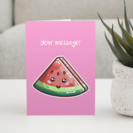A pink greeting card standing on a white table, with a design of a kawaii cute slice of watermelon and personalised with a message above