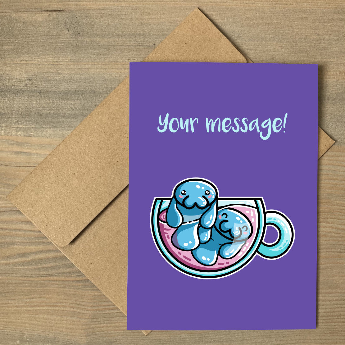 A purple greeting card lying flat on a brown envelope, with a design of two kawaii cute blue manatee swimming in a teacup, with a personalised message above