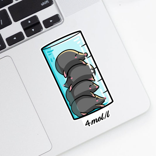 A shaped vinyl sticker of a cylinder of liquid with four mole animals in a pile on top of each other and 4 mol/l written beneath stuck onto the bottom right hand corner of a laptop computer keyboard