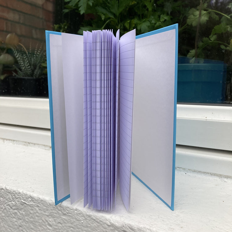 Blue hardback journal standing open showing lined pages within