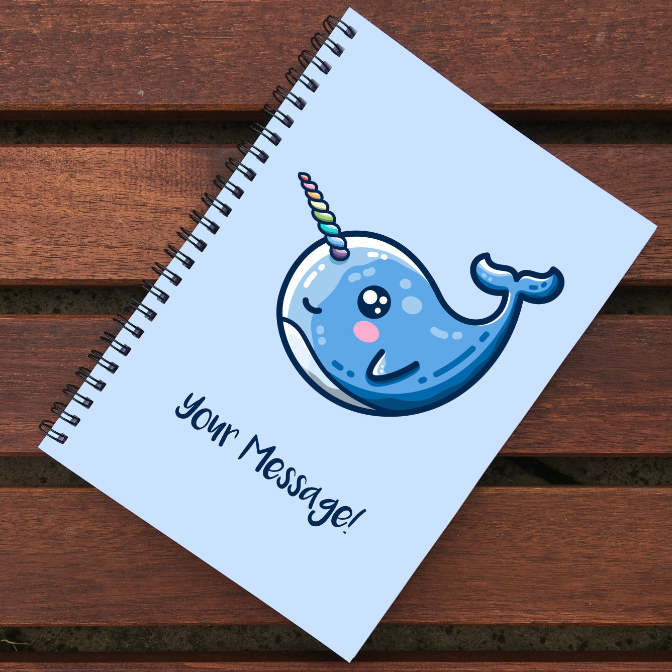 Closed notebook showing blue front cover with personalisation and cute narwhal design