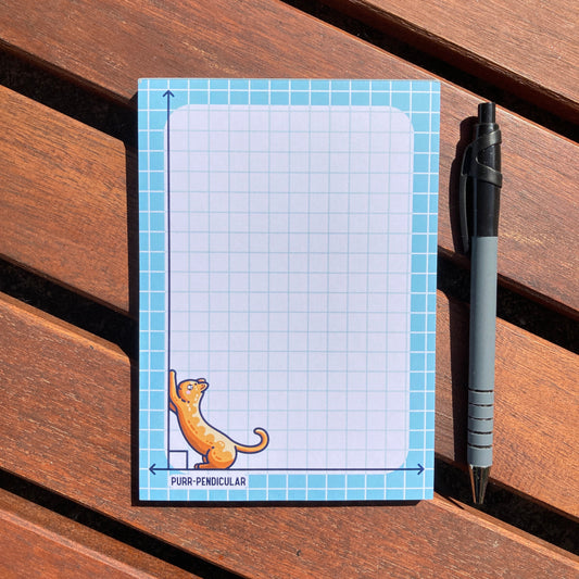 A white notepad with a blue border and blue graph lines. In the bottom left hand corner is a design of a cute ginger cat using a vertical perpendicular line as a scratching post.