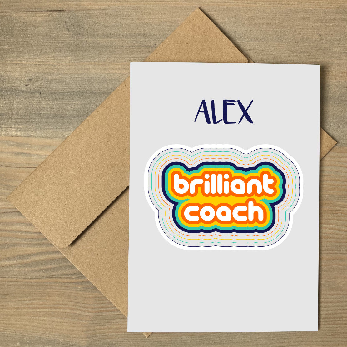 A brown envelope beneath a grey greeting card that features colourful stripes surrounding the words brilliant coach, personalised with a name above.