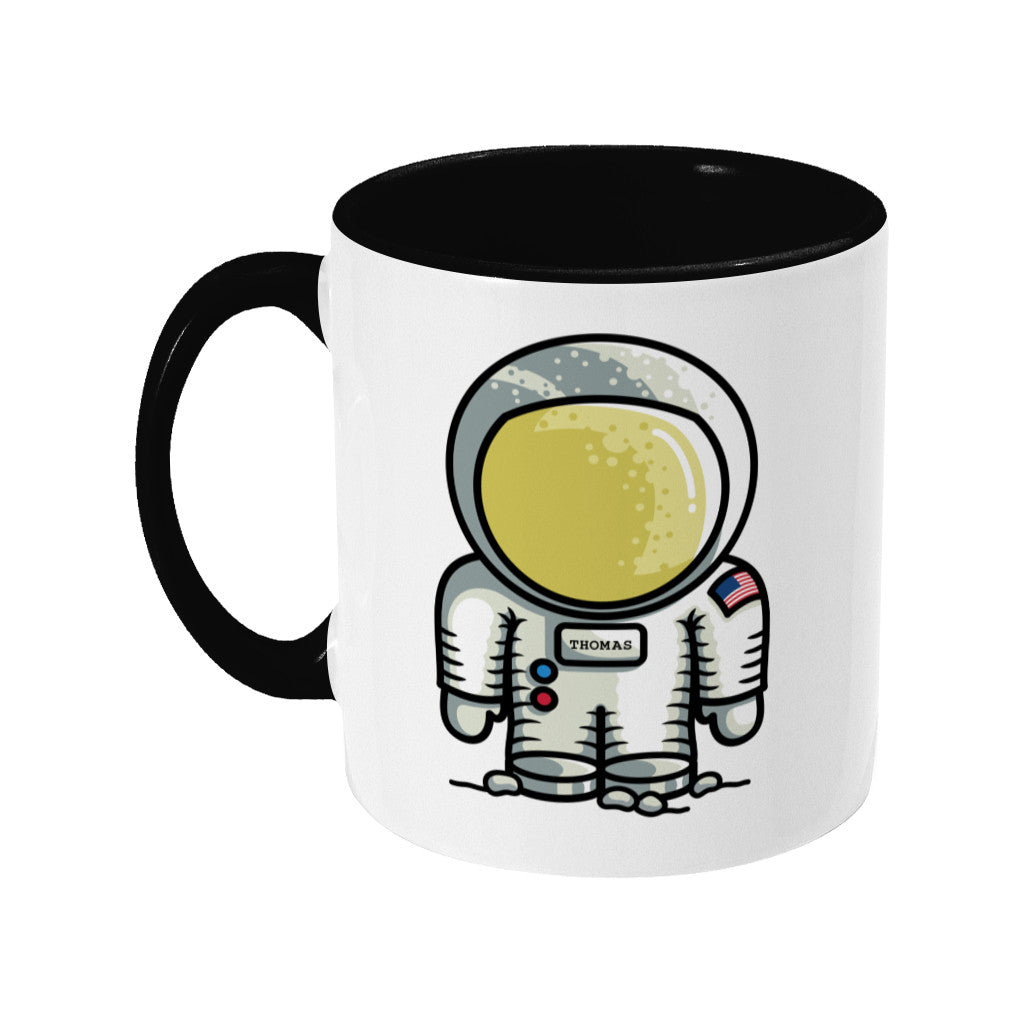 A two toned black and white ceramic mug, handle to the left, with a personalised design of a cute astronaut.