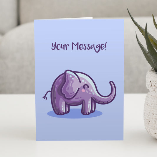 A blue greeting card standing on a white table, with a design of an adorable cute purple elephant facing to the right and with personalised wording above