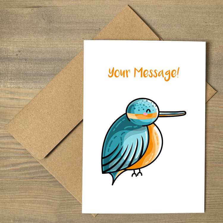 A white greeting card lying flat on a brown envelope, with a design of a cute turquoise and orange kingfisher and a personalised message above