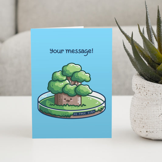 A blue greeting card standing on a white table, with a design of a kawaii cute tree growing in a petri dish and the words above saying 'your message!'
