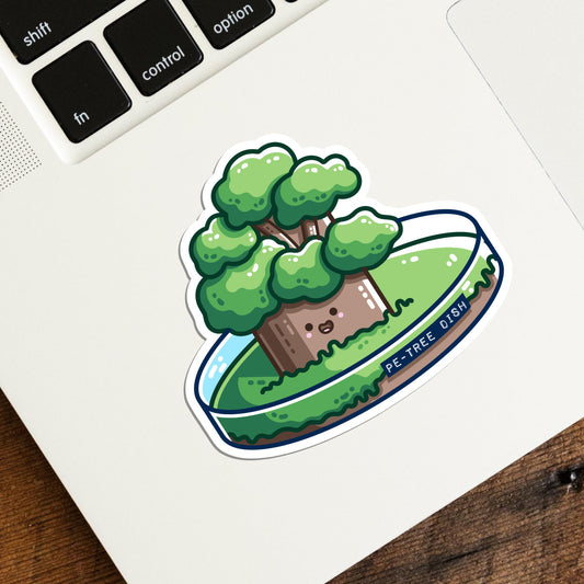 The corner of a laptop keyboard with a vinyl die cut sticker on it, of a kawaii cute tree growing in a petri dish.