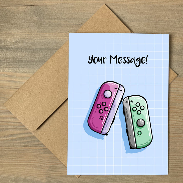 A blue greeting card lying flat on a brown envelope with a design of a purple and green game controller and the words your message written above