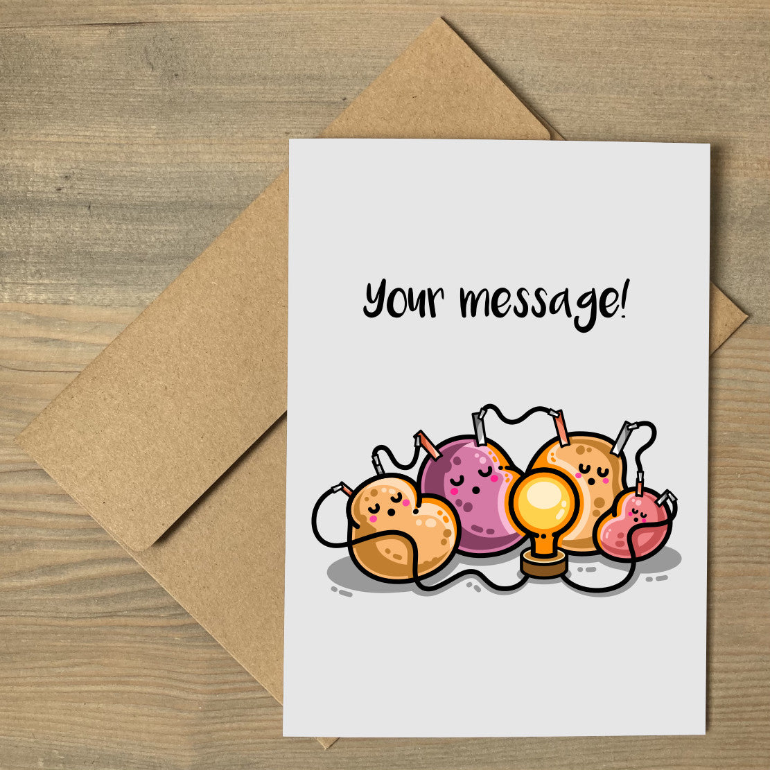 A pale grey greeting card lying flat on a brown envelope, with a design of a potato battery of 4 potatoes asleep around a light bulb they are powering and the words 'your message' written above