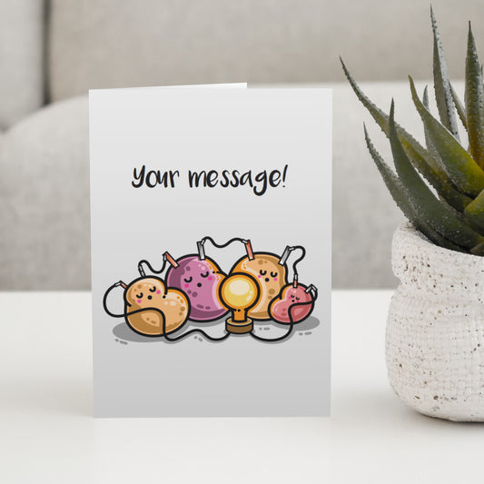 A pale grey greeting card standing on a white table, with a design of a potato battery of 4 potatoes asleep around a light bulb they are powering and the words 'your message' written above