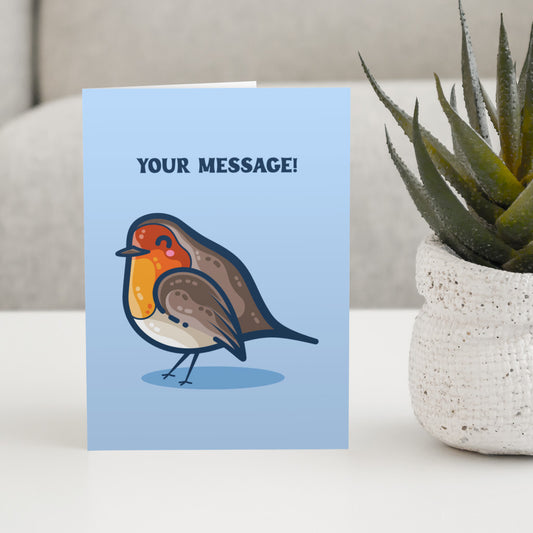 A blue greeting card standing on a white table, with a design of a kawaii cute robin bird facing to the left and your personalised message above